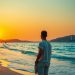 Пляж Турции с пальмами и морем, турист у кромки воды